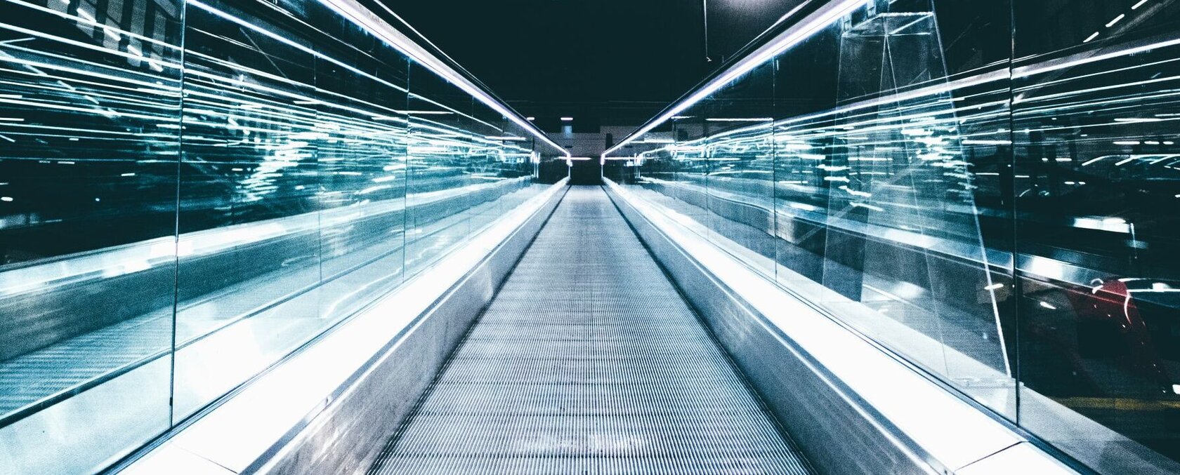 New Mobility City Award – Innovative Mobilität für lebenswerte Städte Blick von unten auf eine Fahrtreppe in Richtung eines dunklen Himmels mit futuristischen Lichtbewegungen